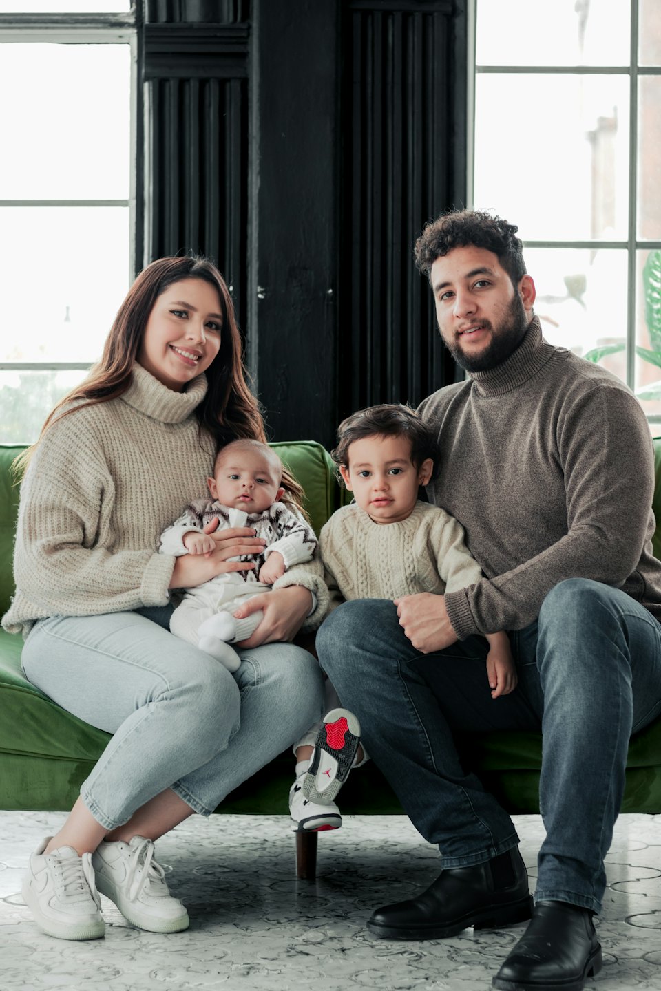Contatti Famiglia con due bambini piccoli seduti su un divano verde.